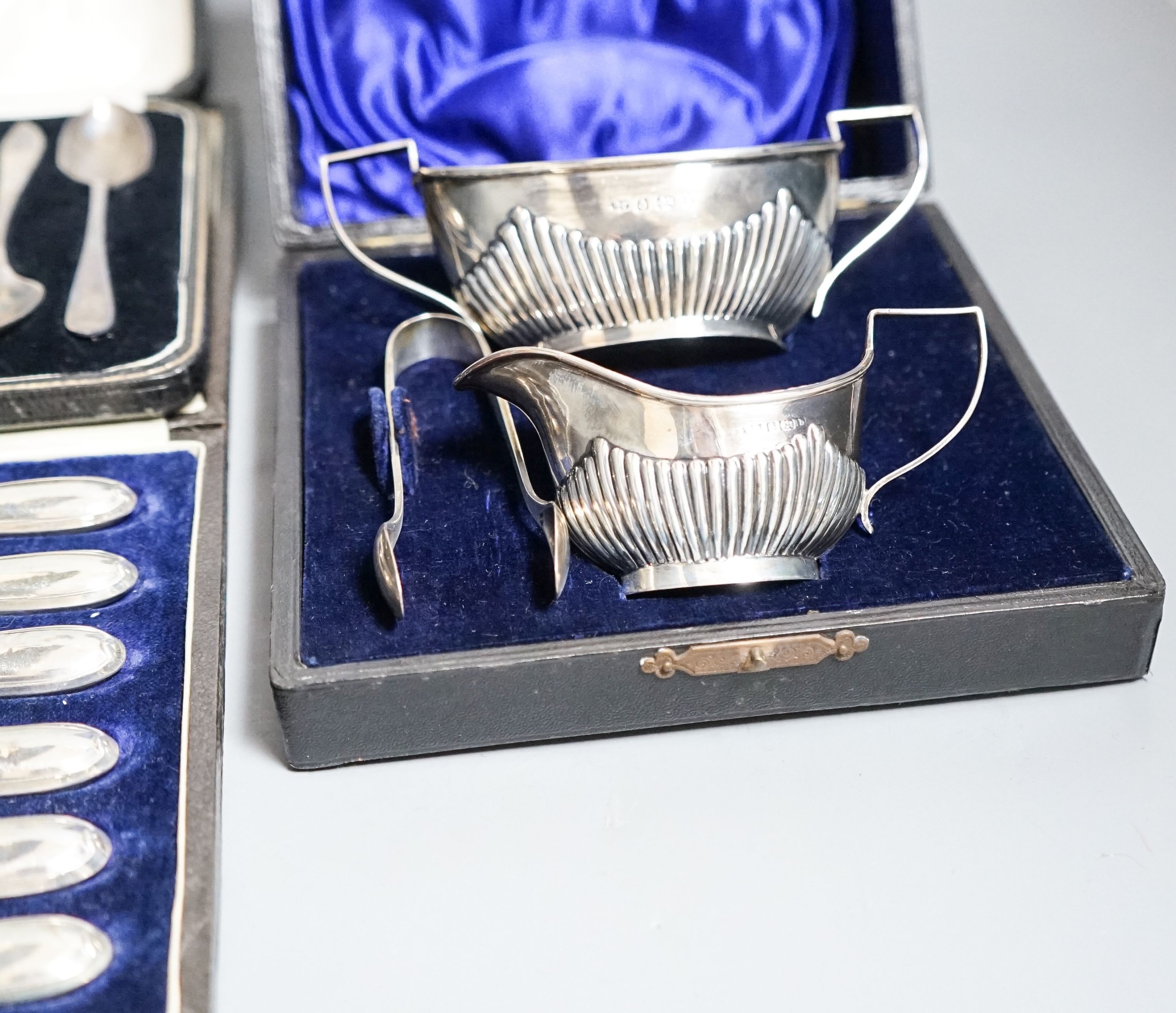 A cased Edwardian silver cream, sugar and sugar tongs, Birmingham, 1901 and two other cased sets of silver cutlery.